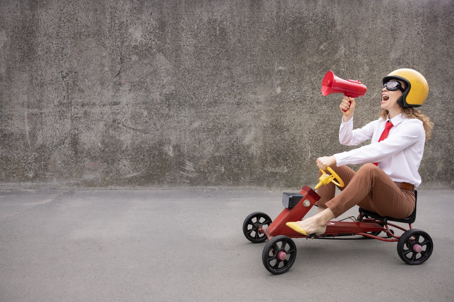 Funny businesswoman driving retro pedal car outdoor